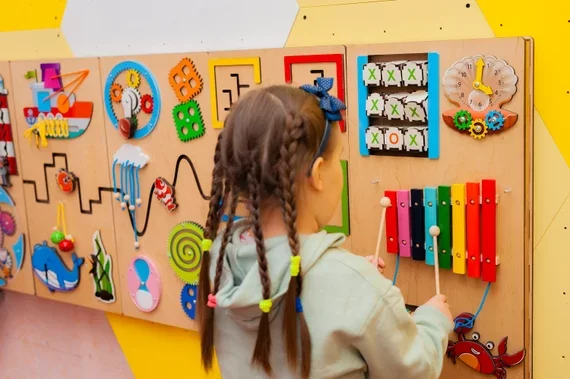 Child Engaging With Tactile Sensory Wall Panels For Motor Skill Development
