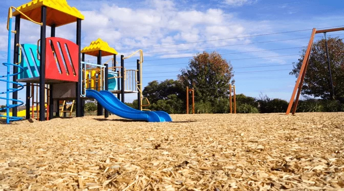 Wood Chip Playground Surface Contained By Pressure Treated Border Timbers In A Community Park